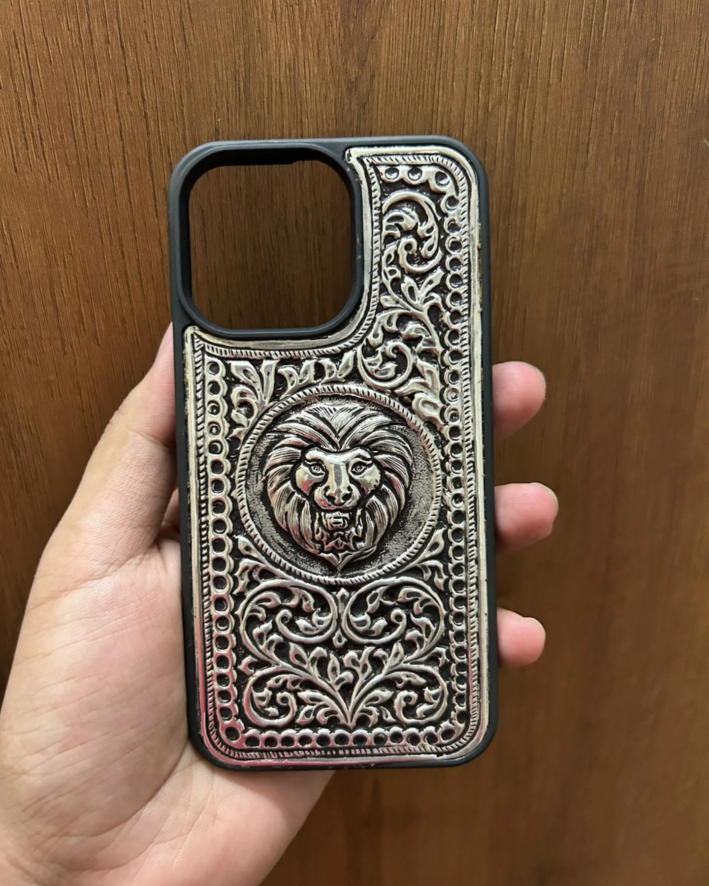 Silver mobile cover with intricate engraved floral and lion face design, premium metallic finish luxury phone case for iPhone showcasing detailed handcrafted artwork and elegant silver texture.
